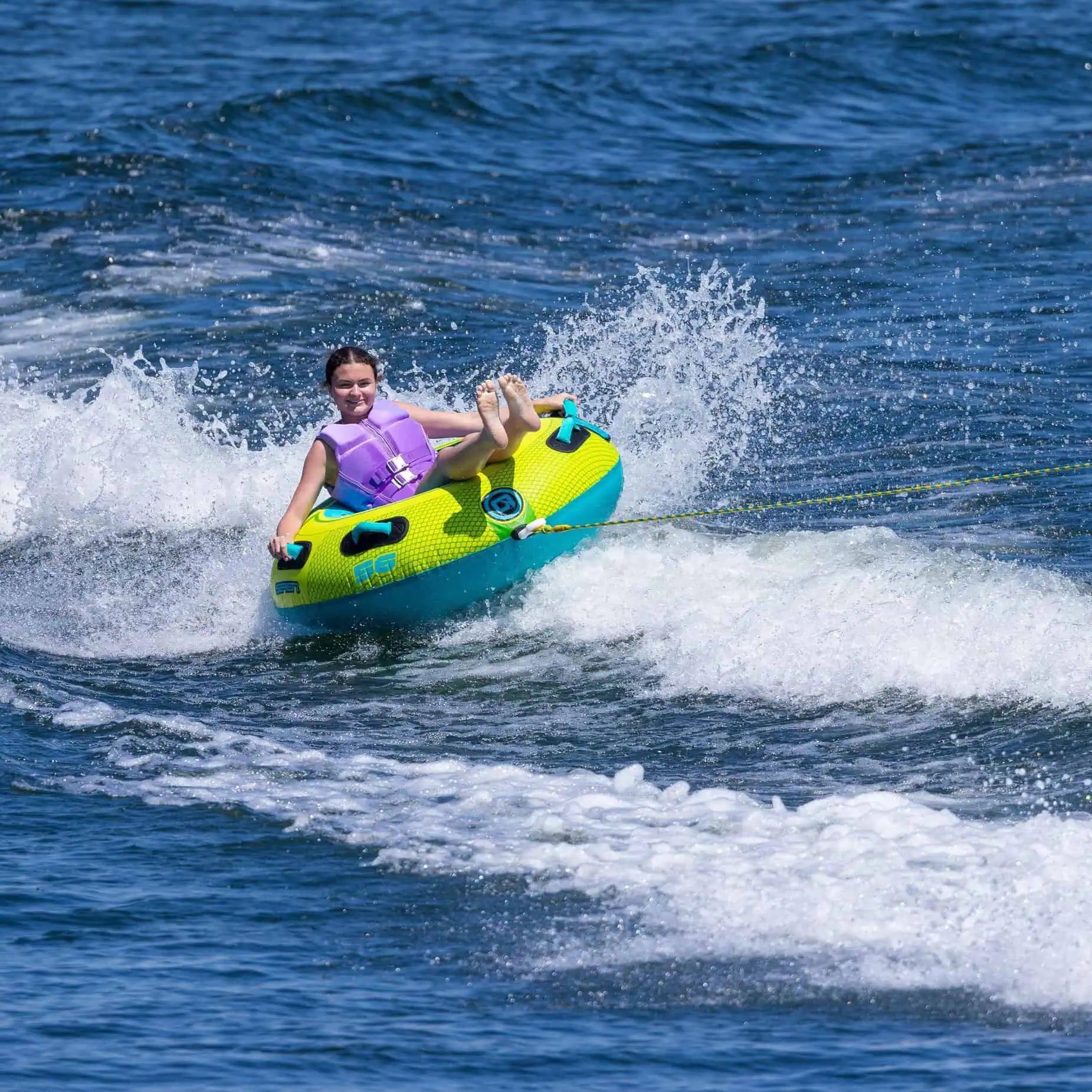 Person on a green and blue O'Brien Le Tube Deluxe - Towable Boat Tube in the water