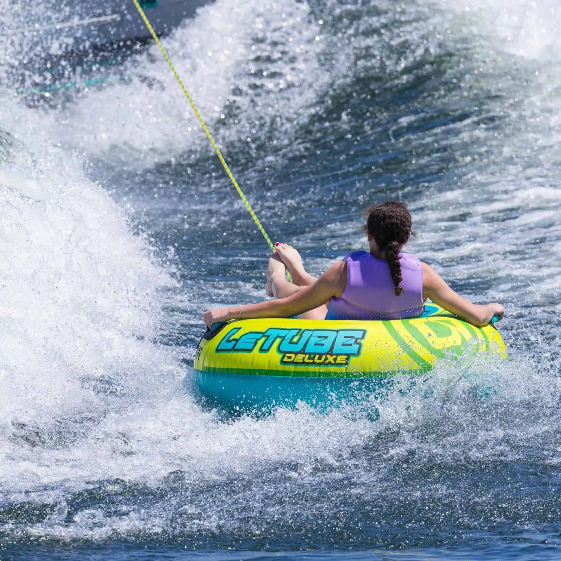 Person on a O'Brien Le Tube Deluxe - Towable Boat Tube being pulled by a rope through the water.