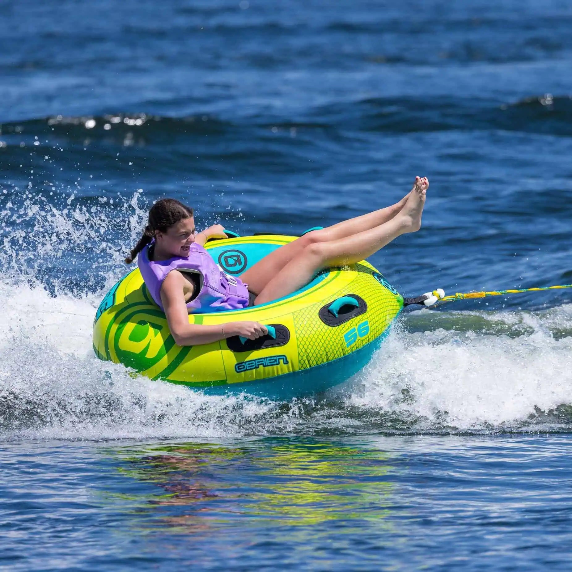 Person on a yellow and blue O'Brien Le Tube Deluxe - Towable Boat Tube in the ocean