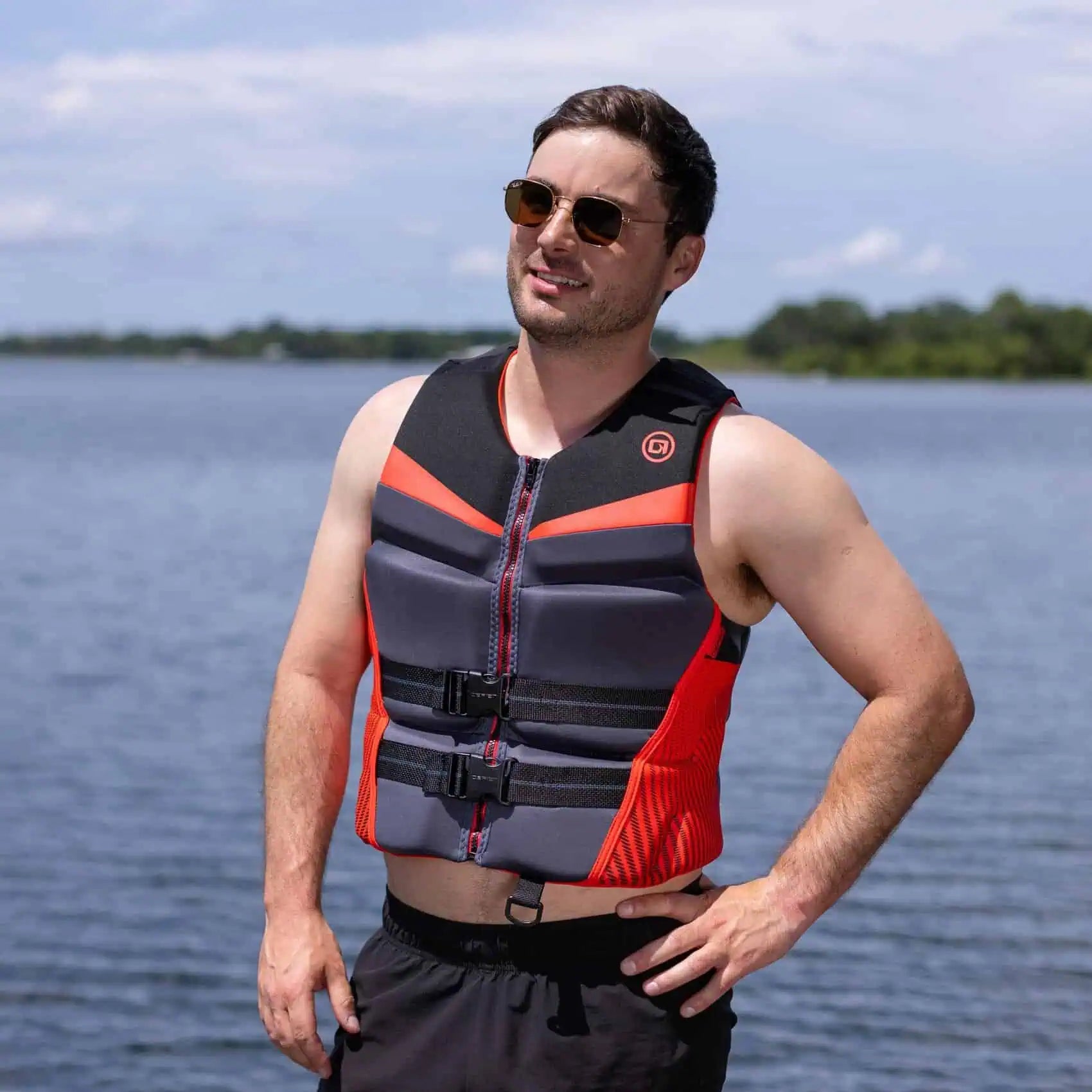 Man wearing a red O'Brien Men's Flex V-Back Life Jacket on a lakeside background