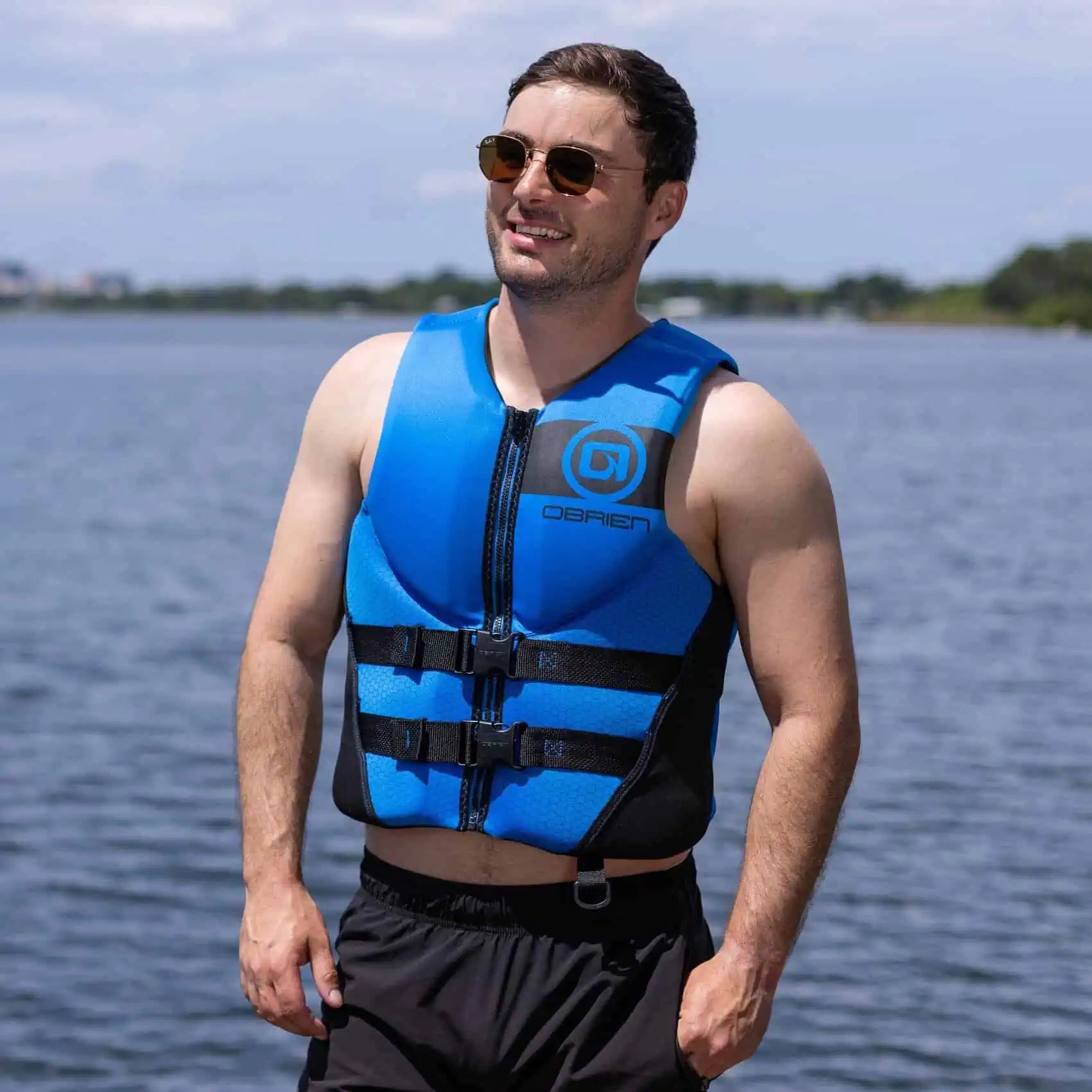 Man wearing a blue O'Brien Men's Traditional Vest on a body of water