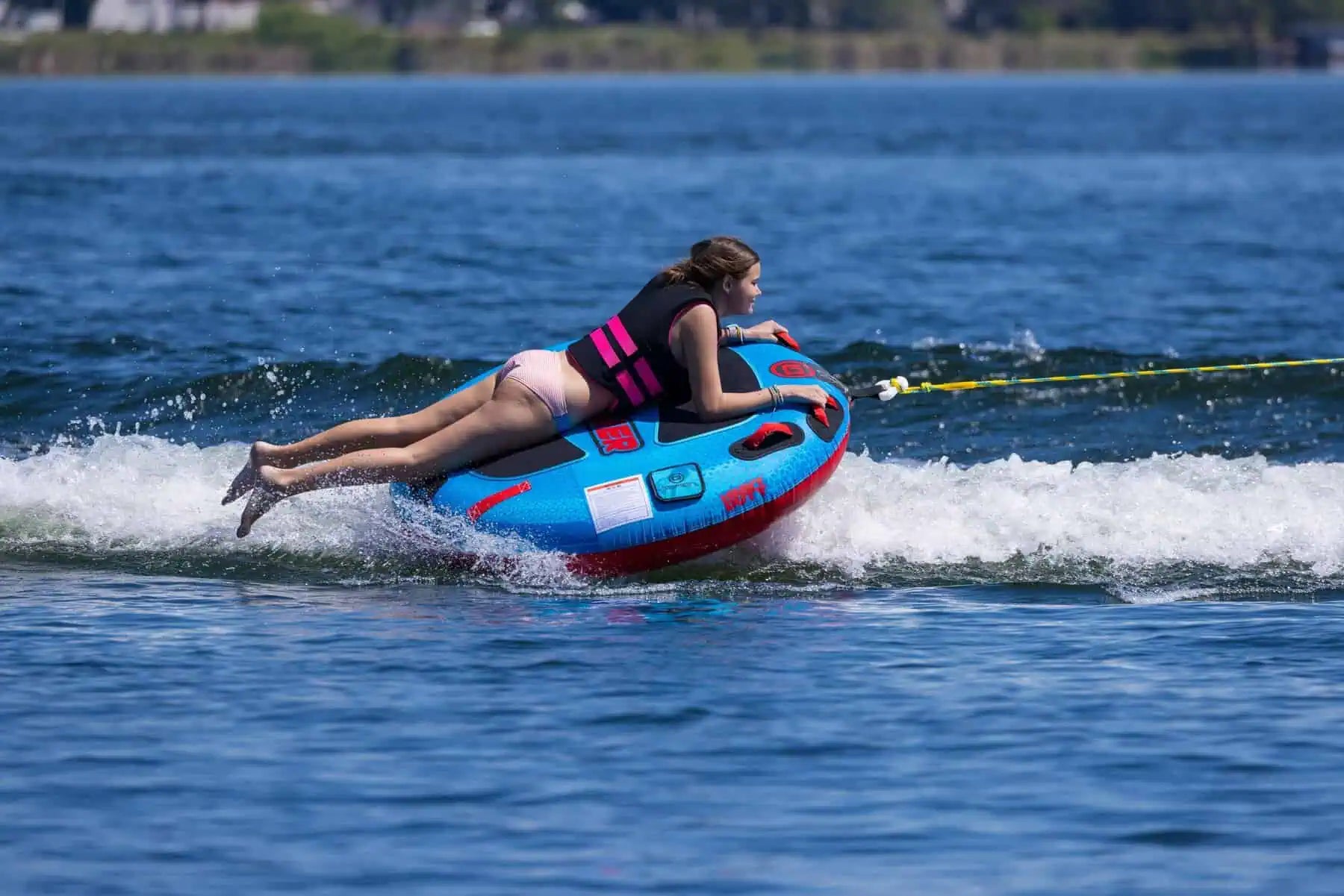 Person riding a blue and red O'Brien Screamer Tube on a lake