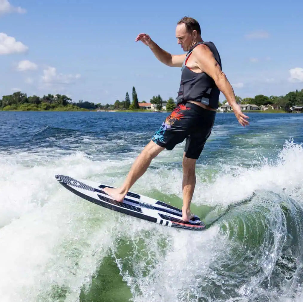 Person wakeboarding on a body of water with trees and buildings in the background