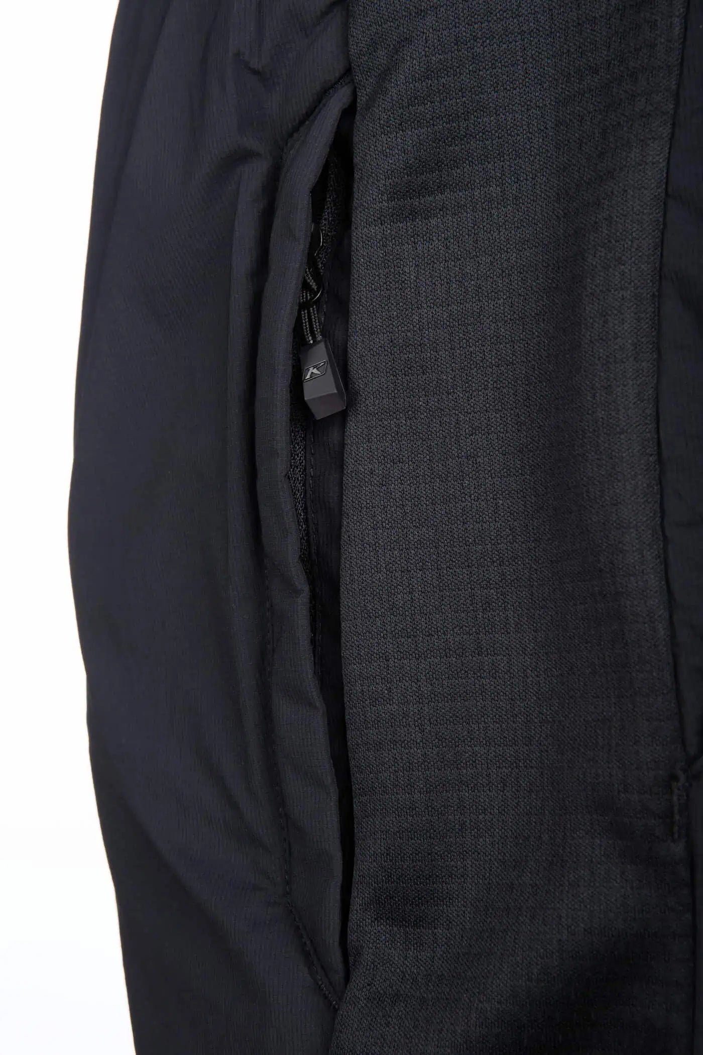 Close-up of a black and gray textured fabric with a zipper detail on a white background detail of Klim Override Alloy Insulated Pant
