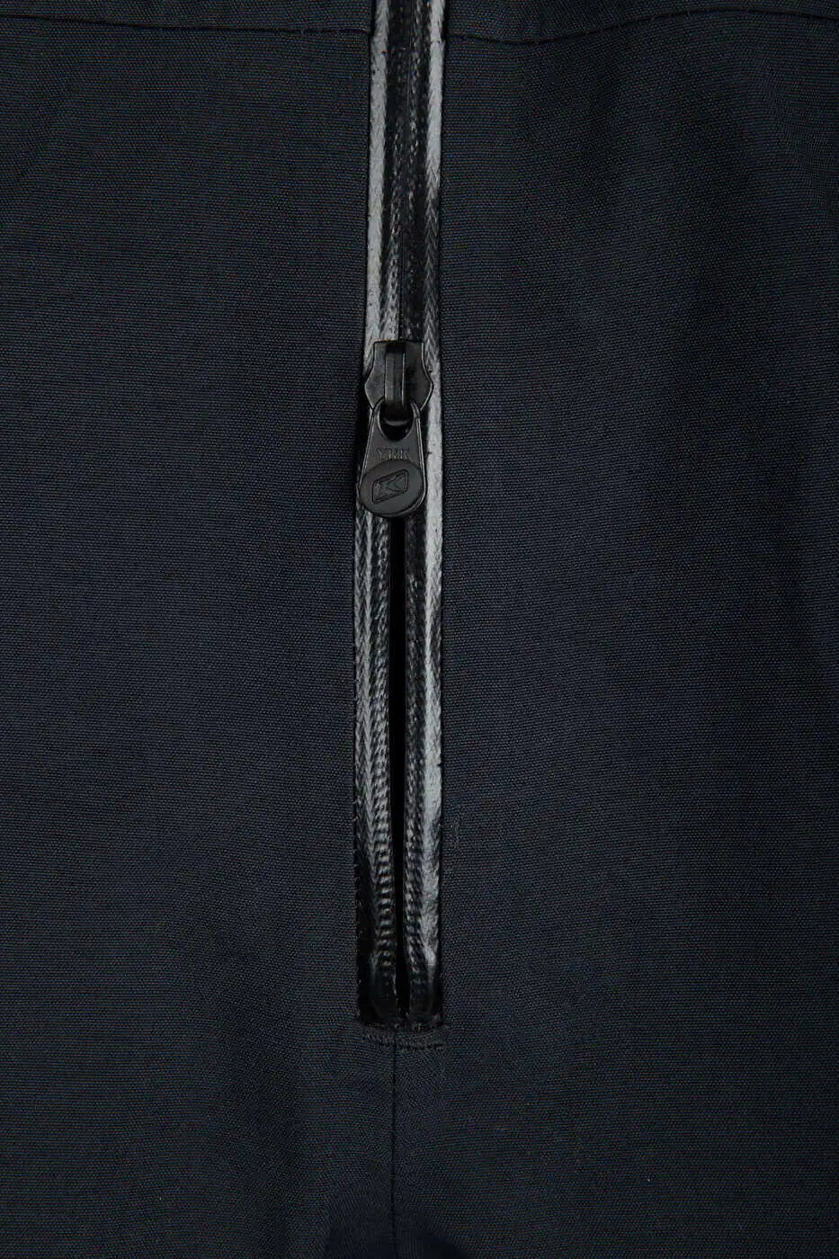 Close-up of a black zippered Klim Togwotee Bib, showing a black zipper pull and a black fabric body.