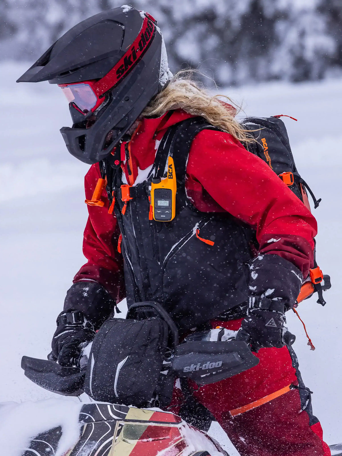 Person in winter gear with a helmet and goggles, with the BCA BC Link Mini Radio on the arbag