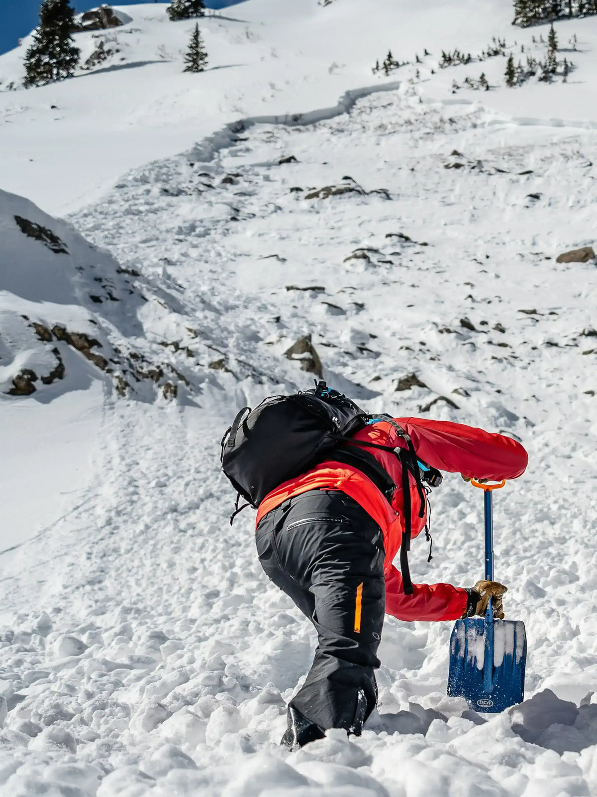 Person on a snowy mountain with a backpack and BCA Dozer™ 2-D Avalanche Shovel