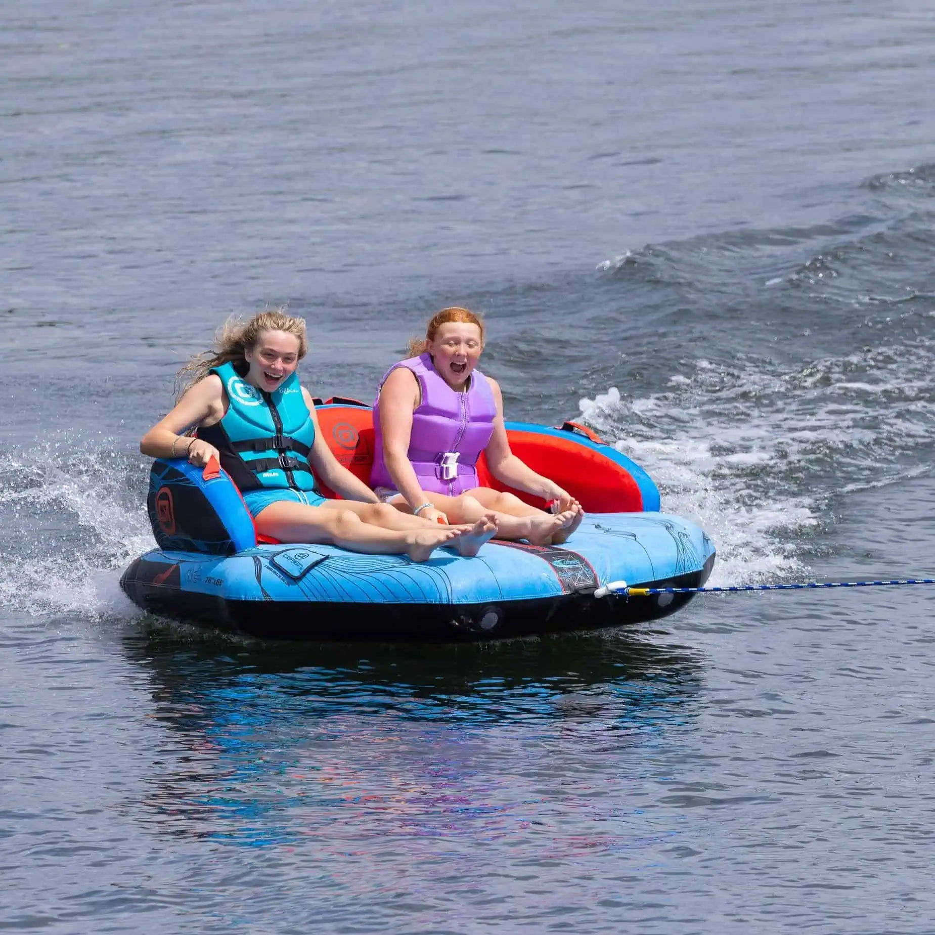 Two people on a blue and red O'Brien Specter 2 Boat Tube in the water