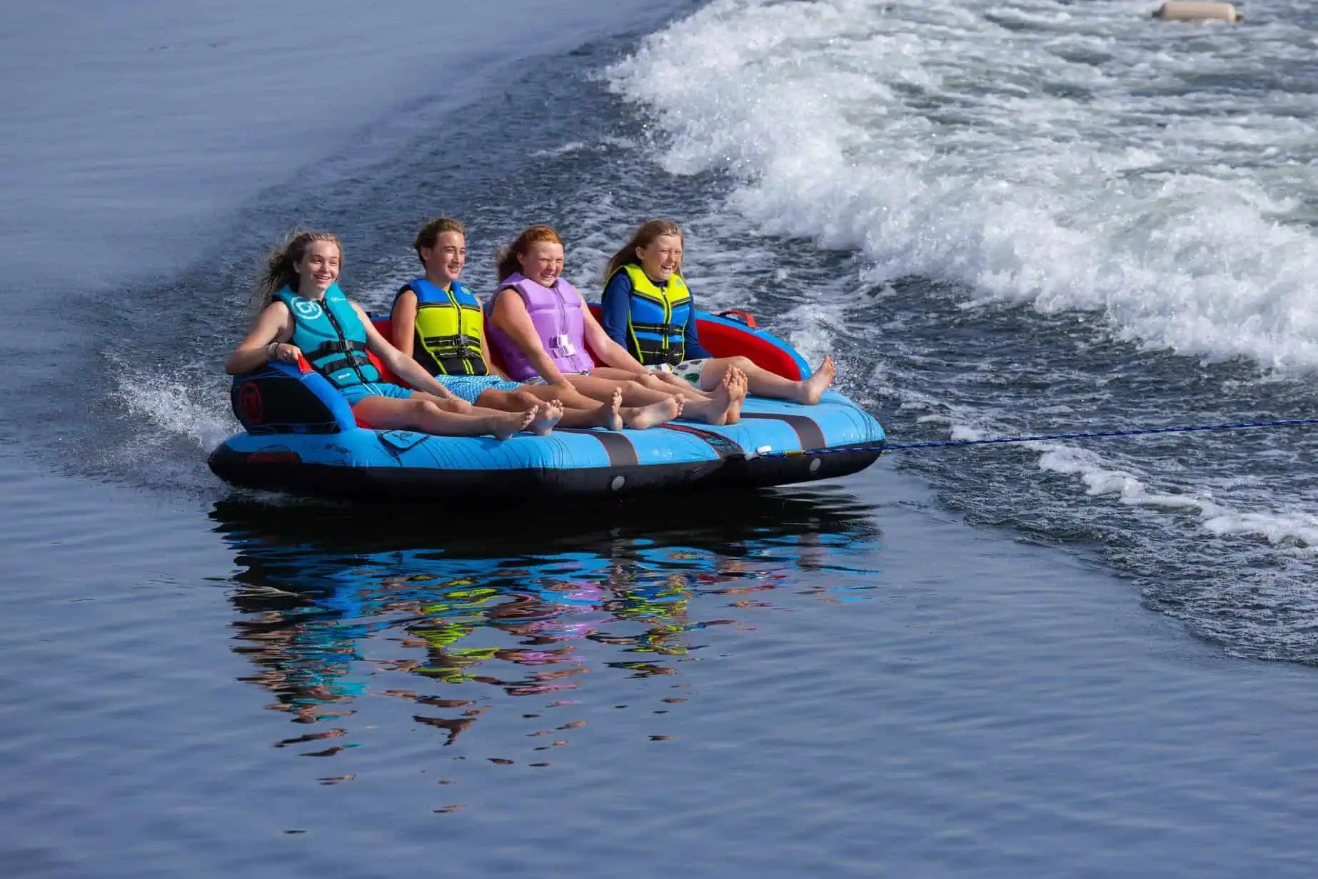 Four people on a blue O'Brien Specter 4 Boat Tube in the water with waves.