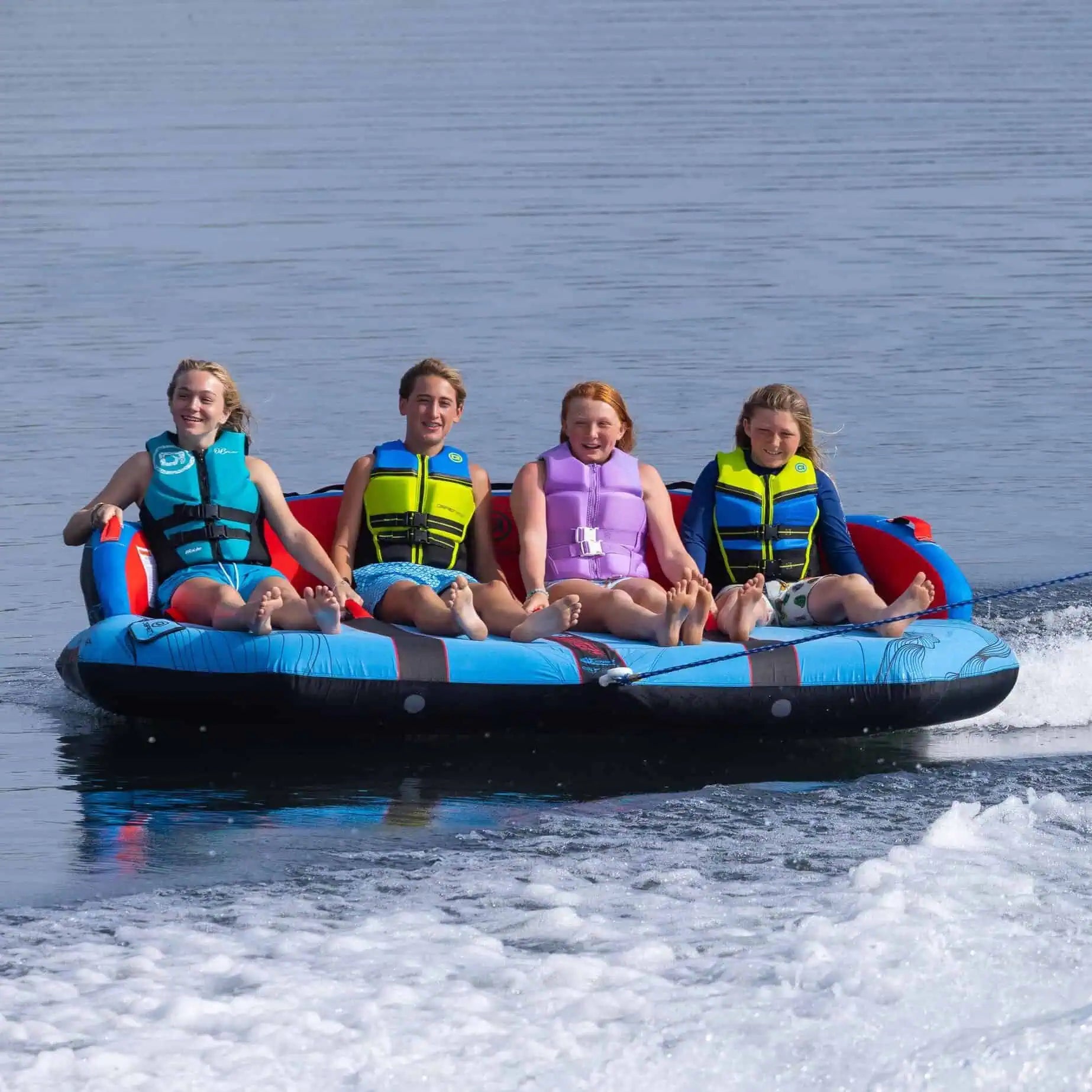 Four children on a blue and red O'Brien Specter 4 Boat Tube in the water