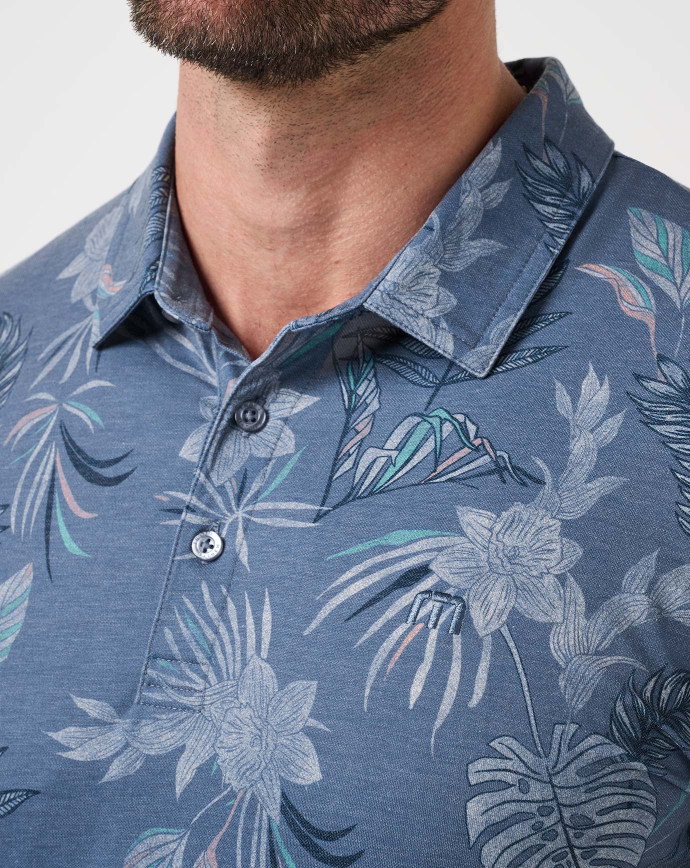 Close-up of a blue floral patterned polo shirt -= TravisMathew Featherweight Reservation Polo Shirt