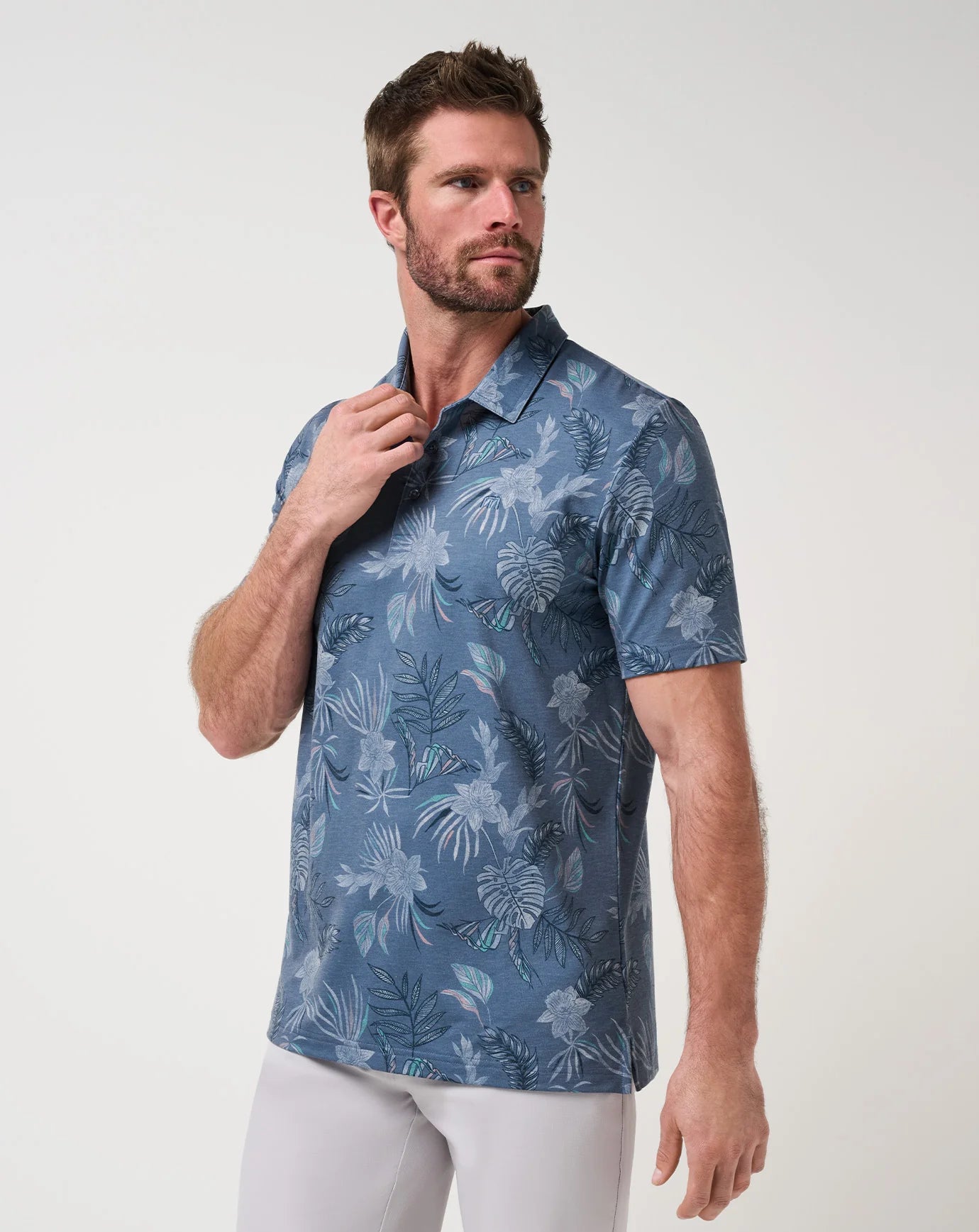 Man wearing a blue floral patterned TravisMathew Featherweight Reservation Polo Shirt