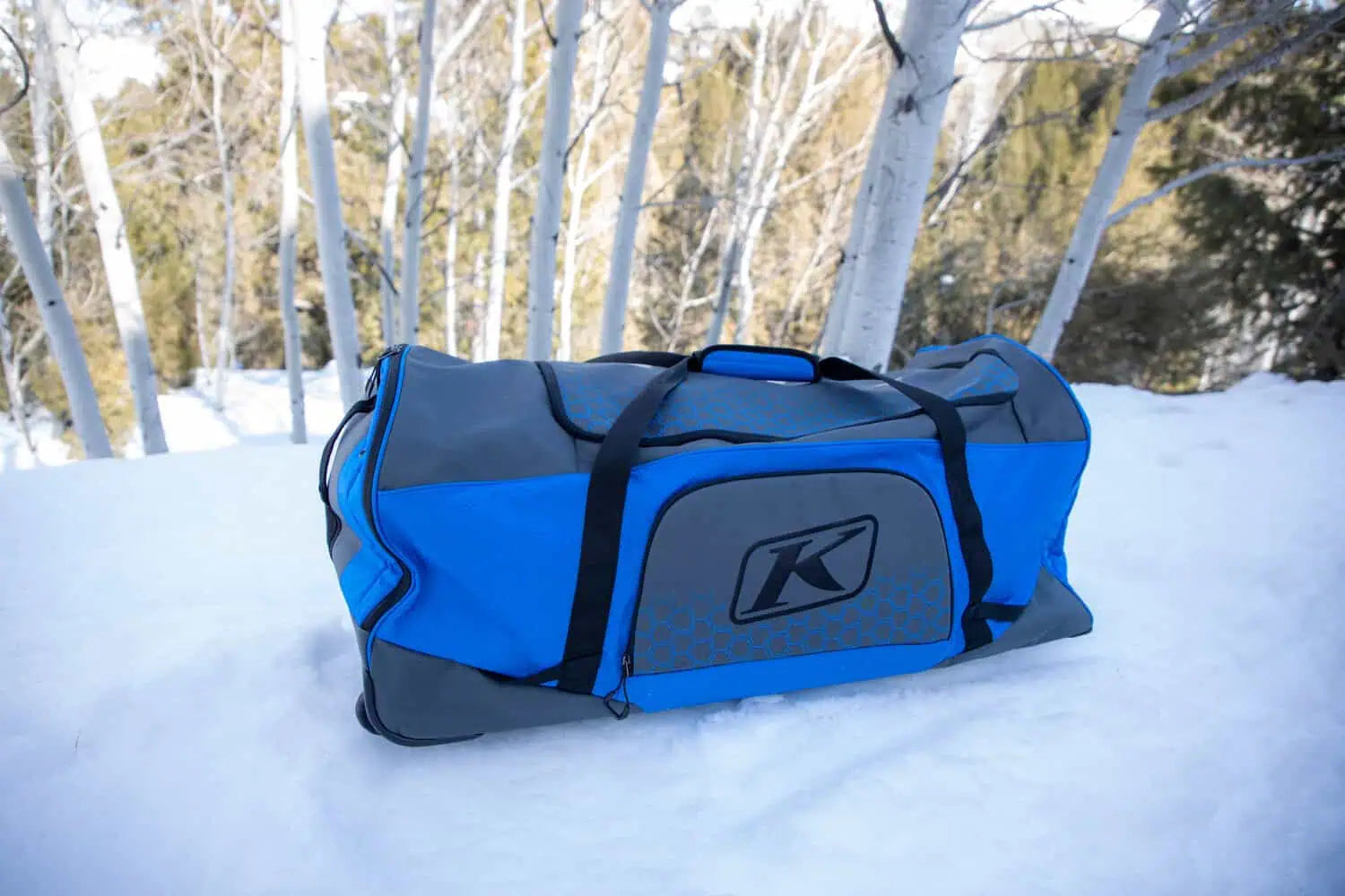 the Electric blue lemonade Klim Team Gear Bag is outside on the snow