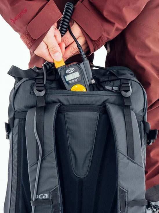 Person putting a BCA BC Link Two-Way Radio 2.0 in a backpack