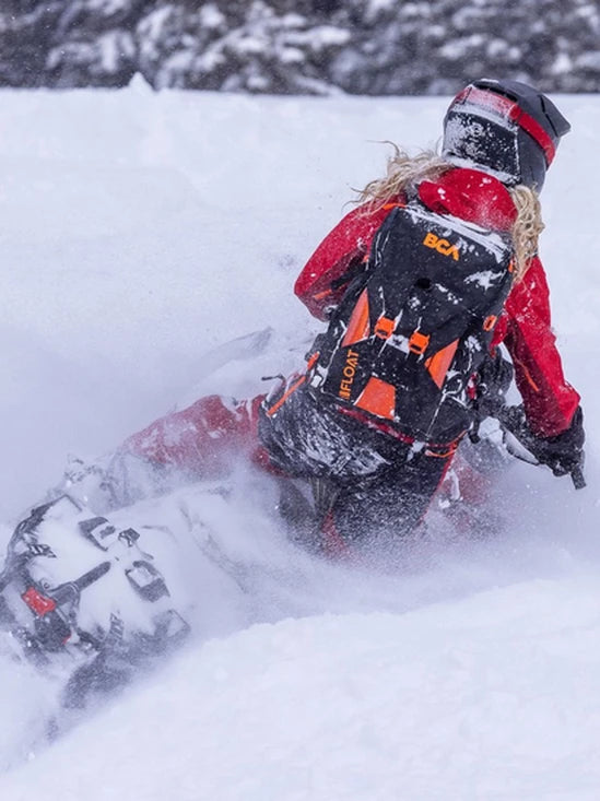 the BCA Mtn Pro Tunnel Bag buried in snow while a rider is on a snowmobile