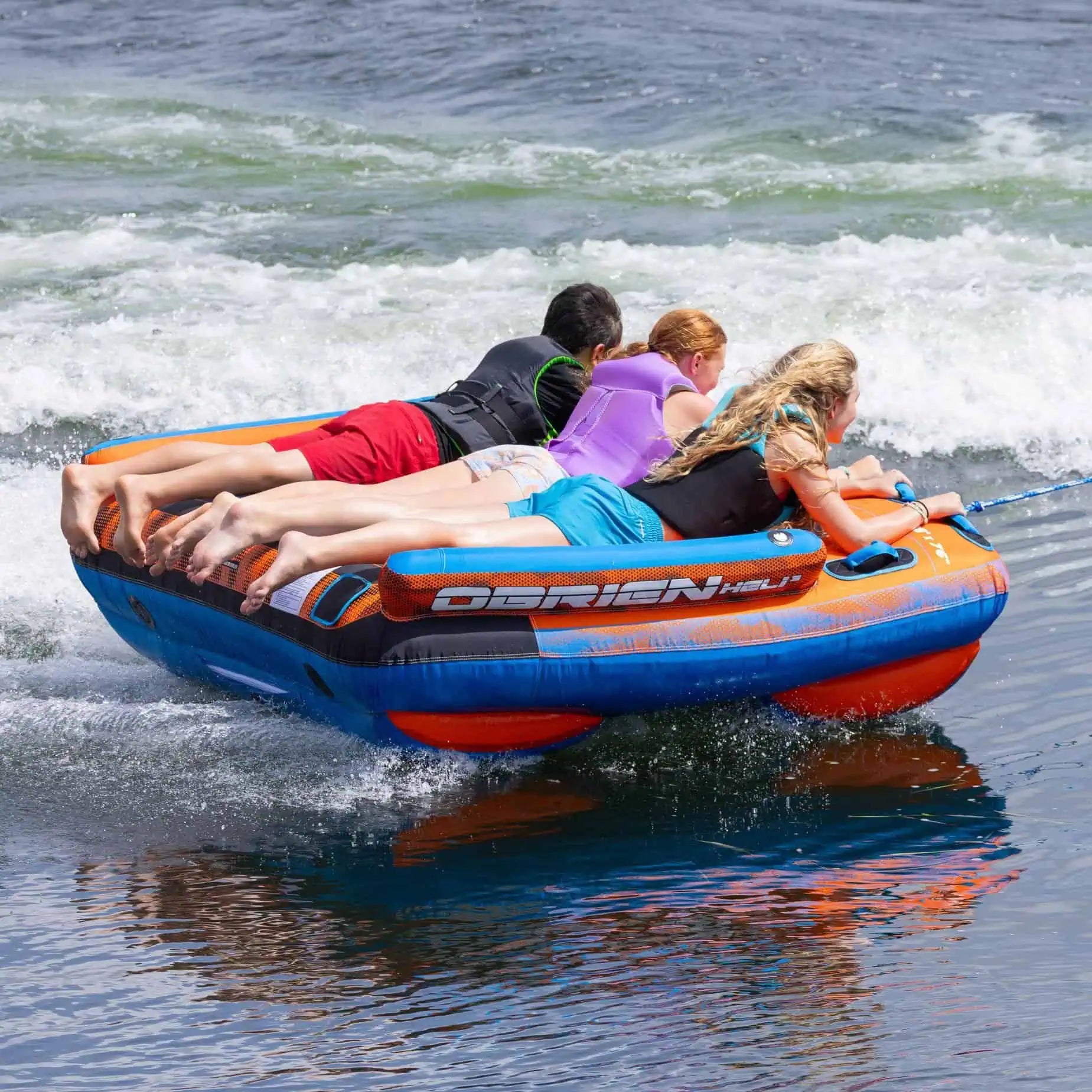 People on an inflatable O'Brien Heli 3 Boat Tube being pulled by a boat on water