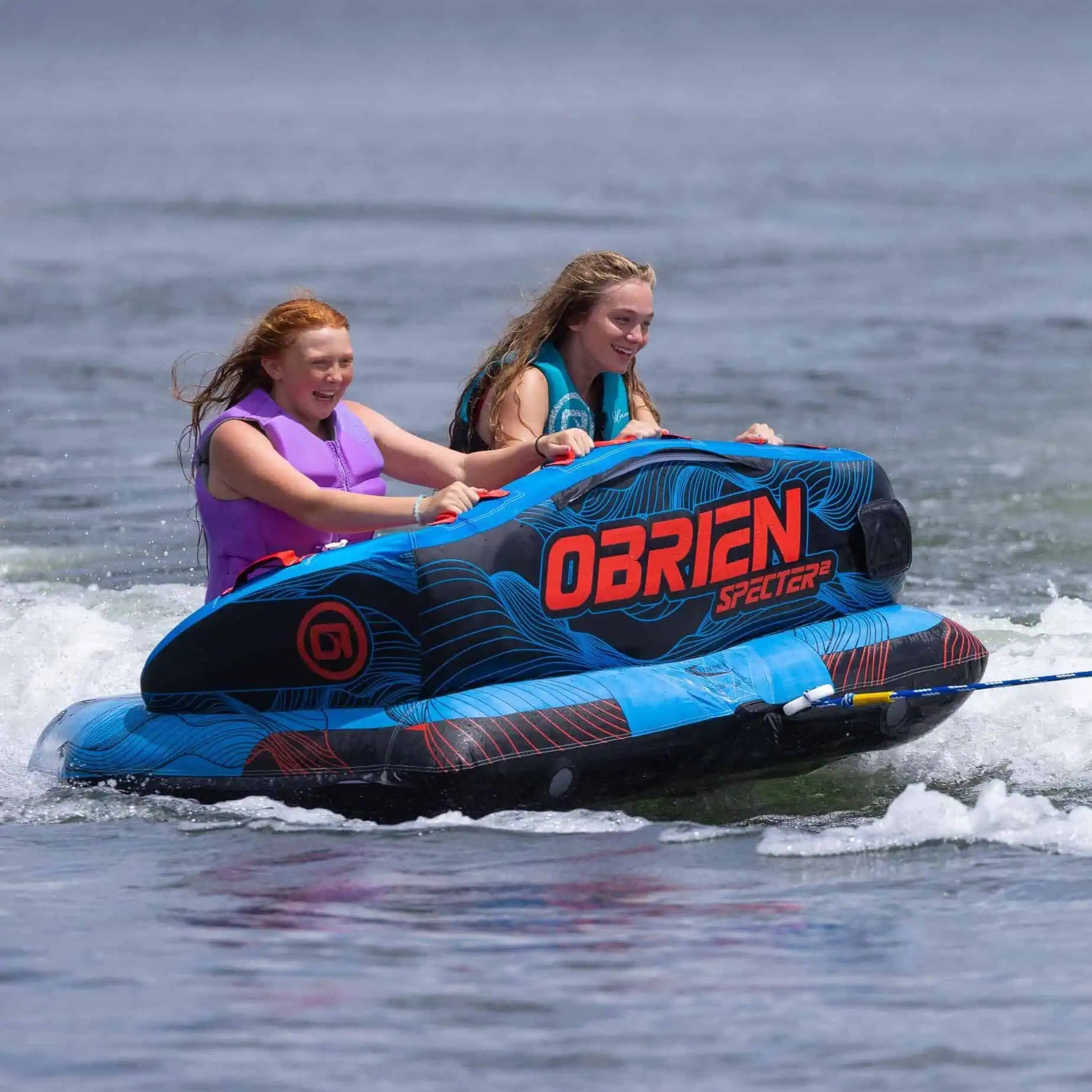 Two people on a blue and black O'Brien Specter 2 Boat Tube in the water.