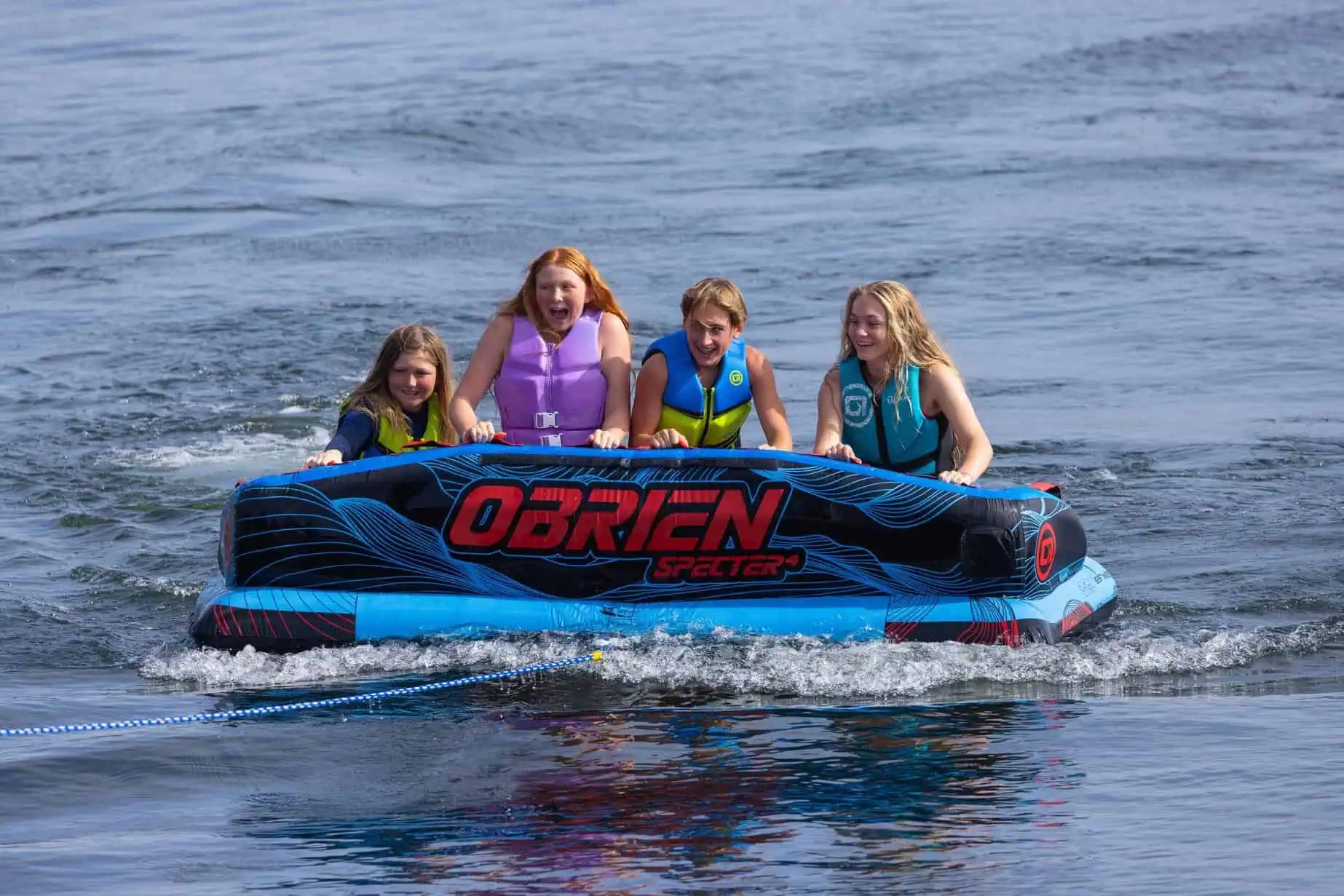 Four people on a blue O'Brien Specter 4 Boat Tube in the water.