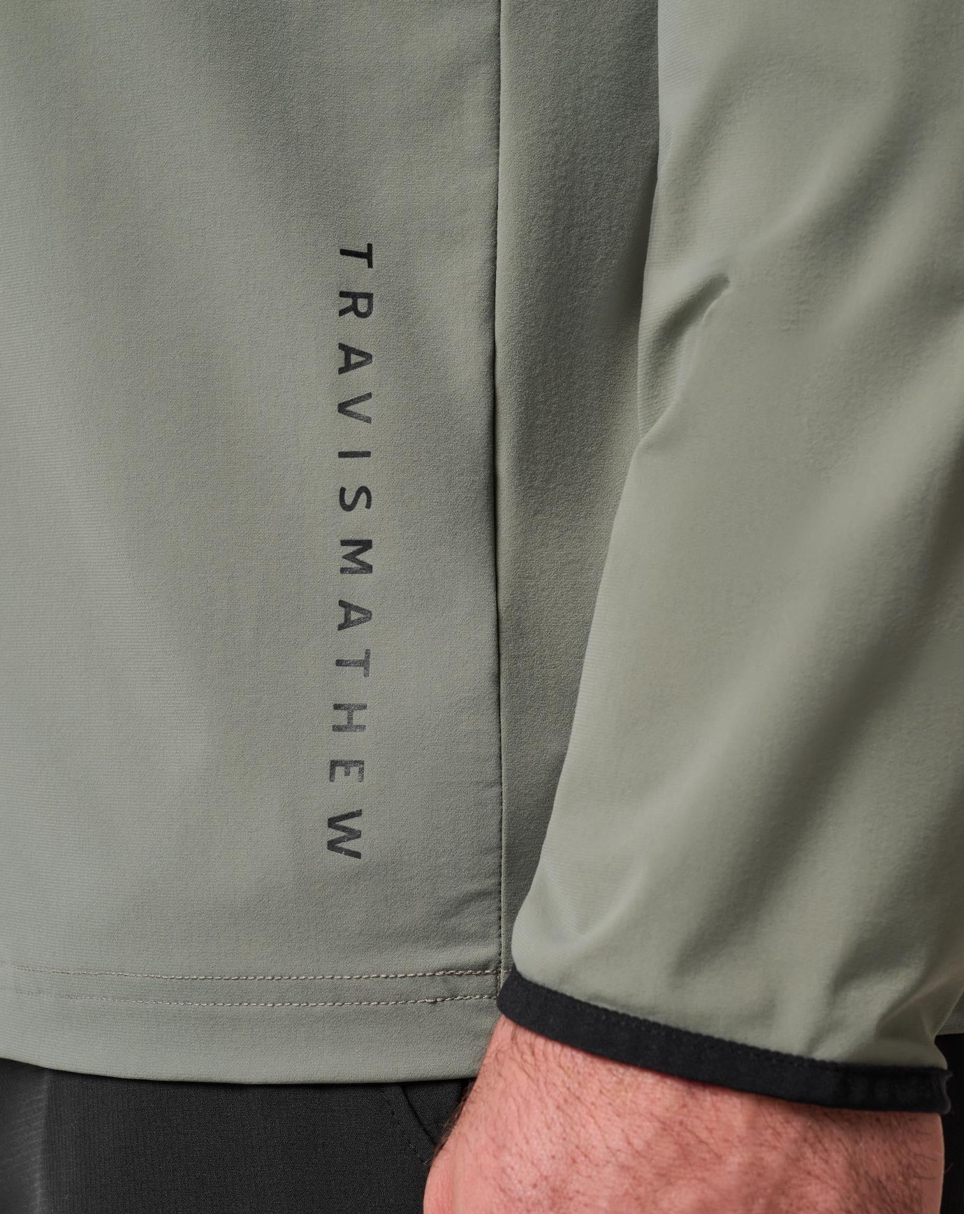 logo detail on "dark olive" TravisMathew Hero Hour Tech Hoodie 