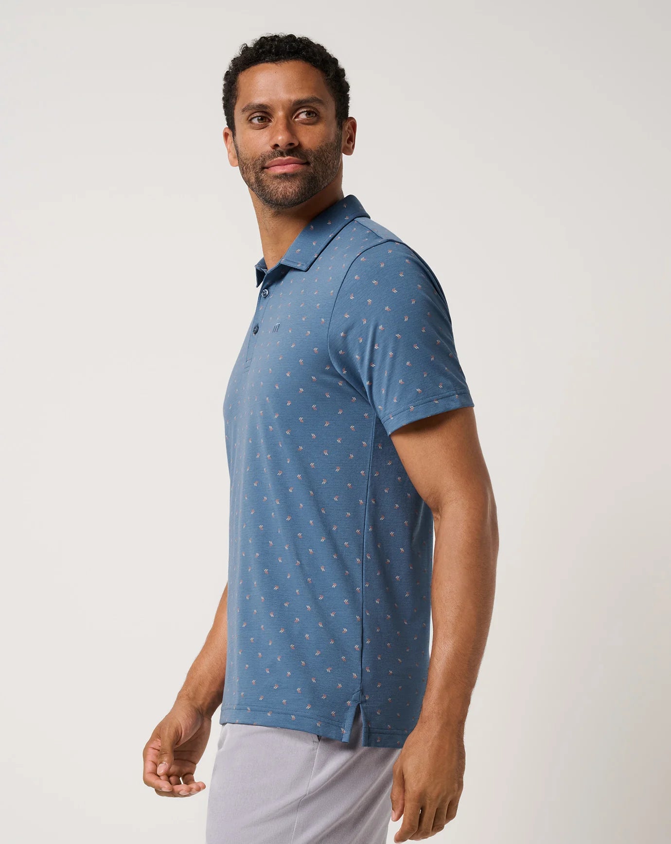 Man wearing a blue TravisMathew Performance Jersey Resort Polo Shirt